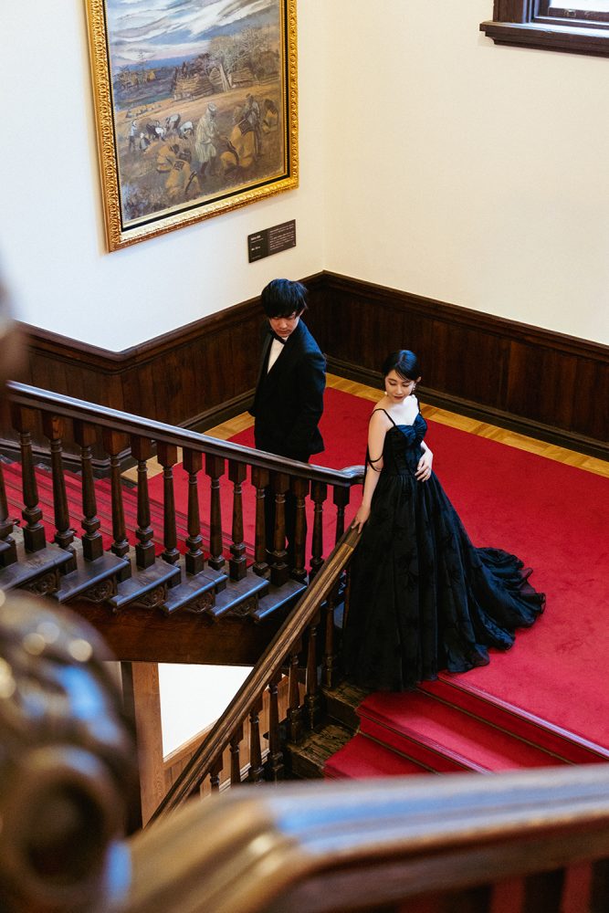 赤れんが庁舎の階段を上る黒ドレスの花嫁と新郎