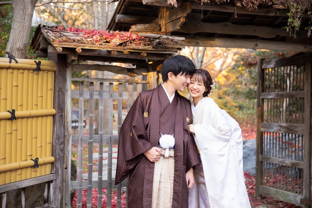 紅葉の真鍋庭園の門の前で寄り添う和装のふたり