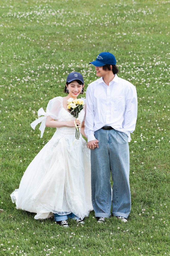 モエレ沼公園の芝生に立つドレスの花嫁と新郎