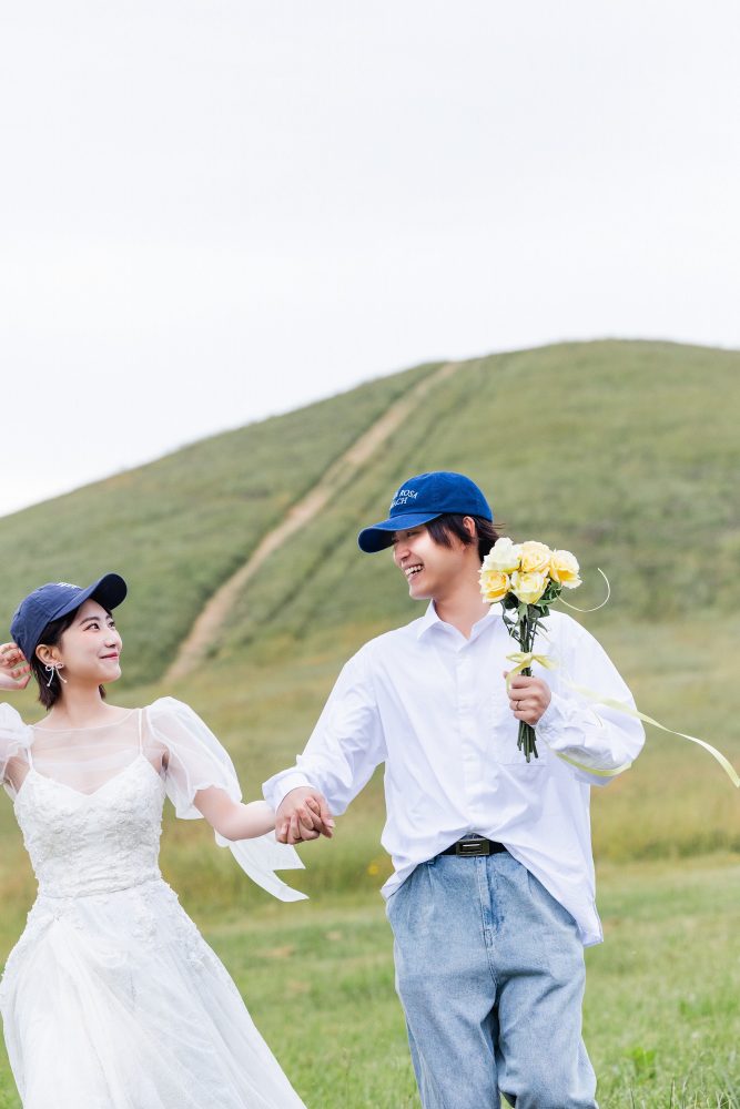 モエレ山を背に手をつないで笑うふたり