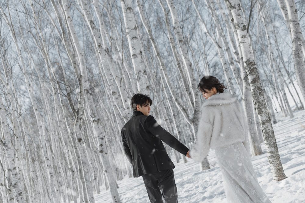 雪の木立を手をつないで歩くふたり(モエレ沼公園)