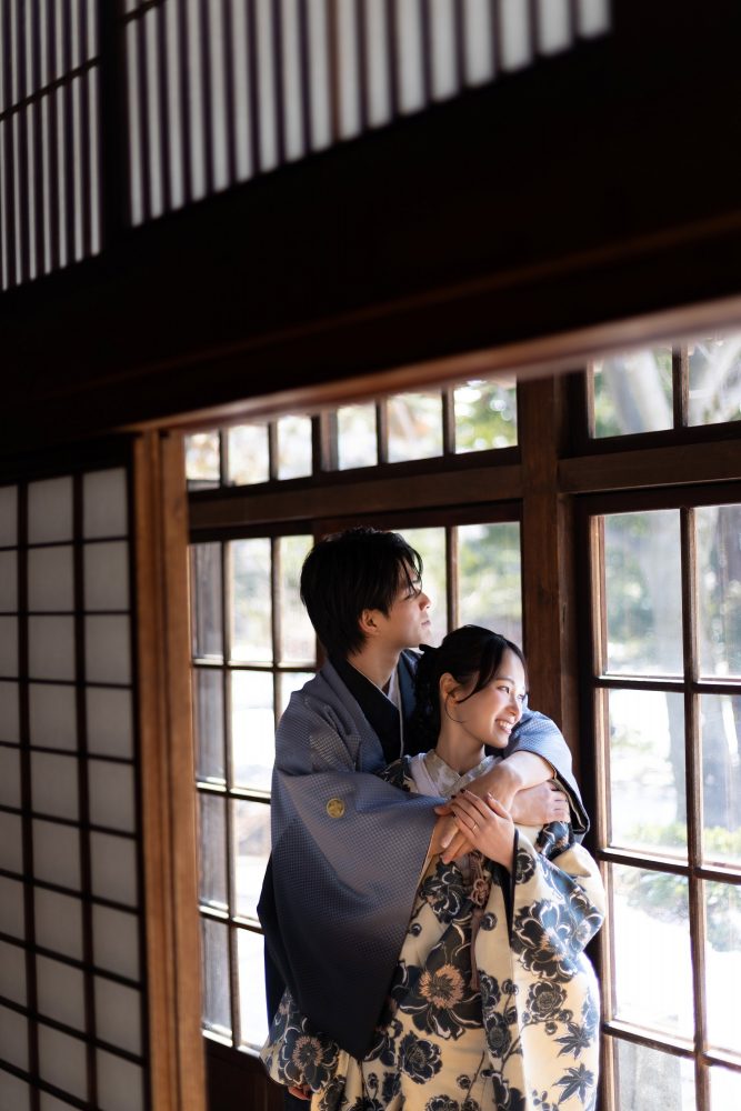 旧永山邸の洋間の窓辺で笑い合う和装のふたり
