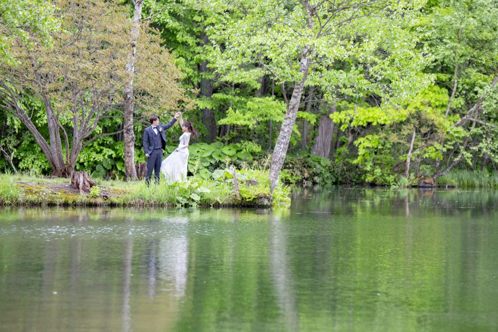 鳥沼公園の水辺に立つドレスの花嫁と新郎