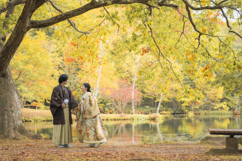 紅葉の鳥沼公園の水辺に立つ和装のふたり